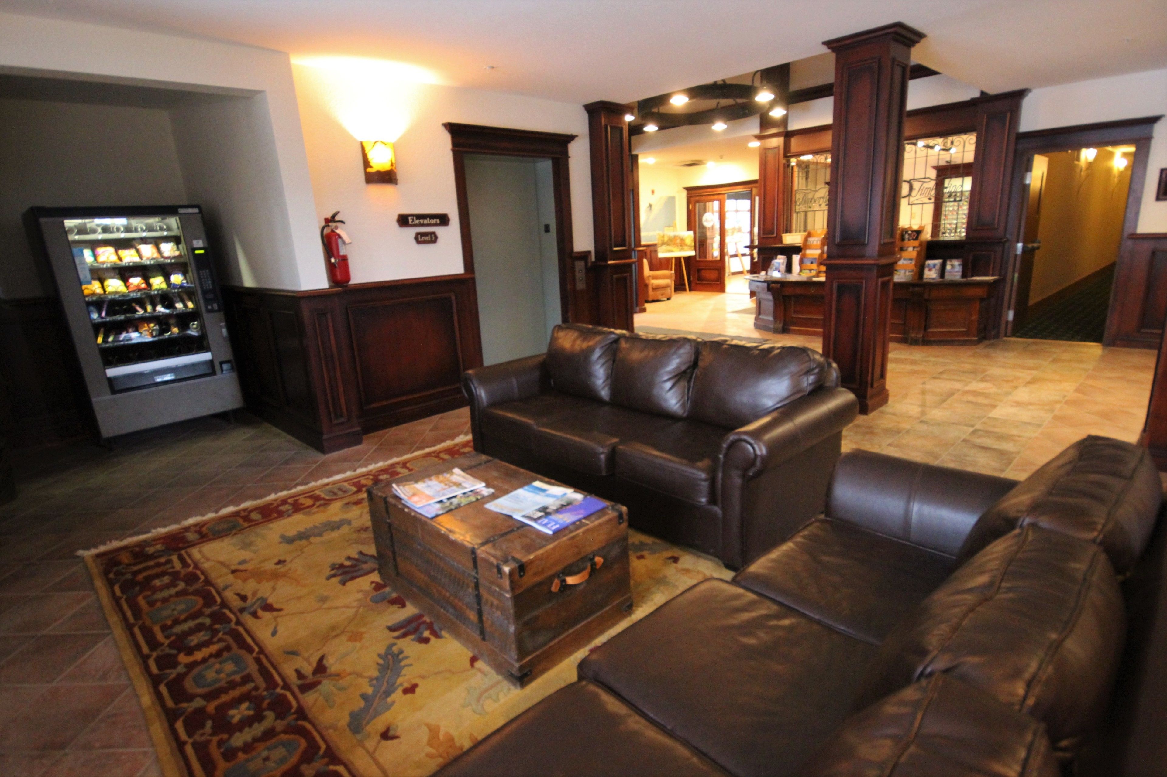 A spacious living room with a leather sofa, a coffee table with magazines, and a vintage trunk.