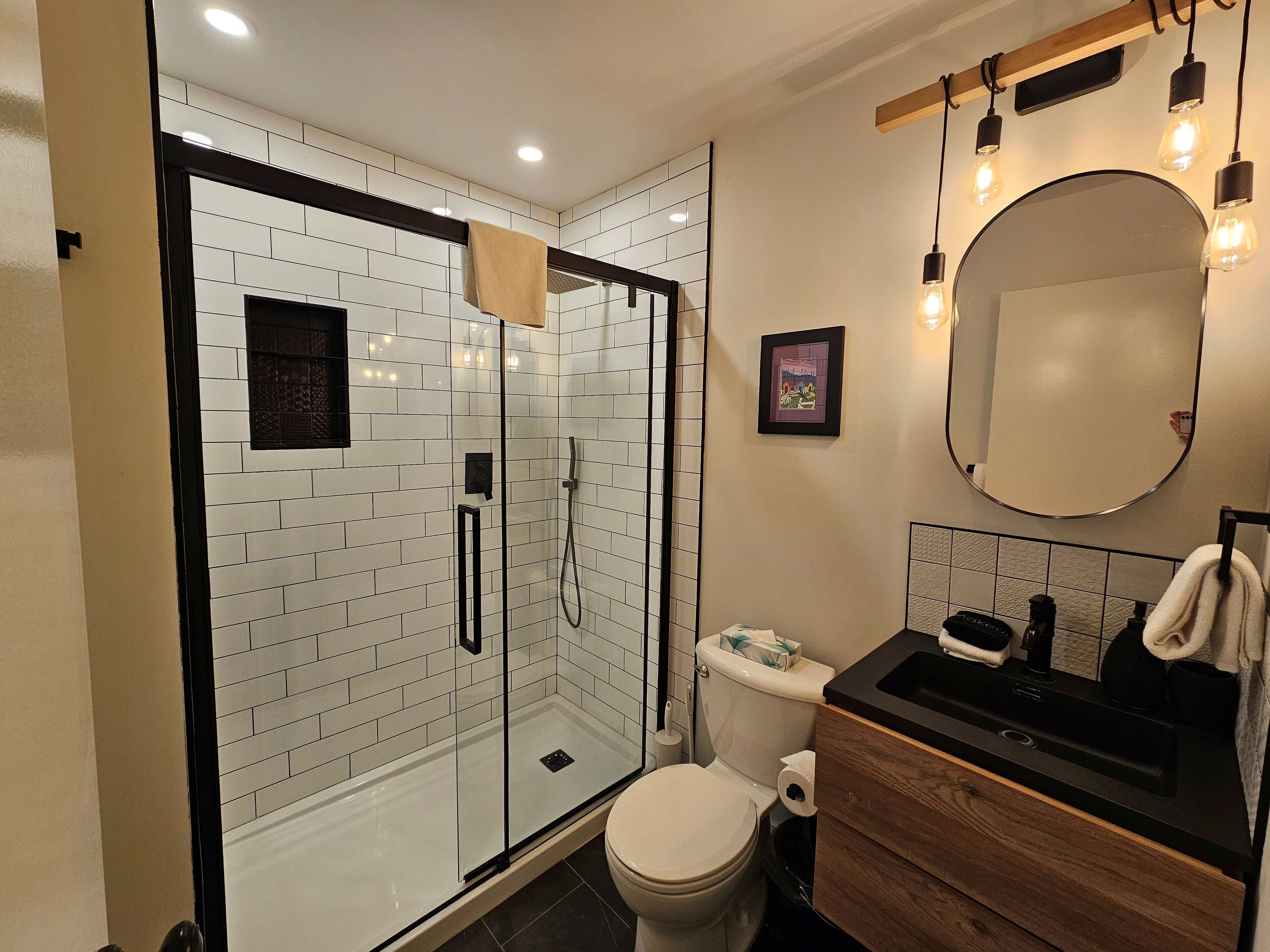 A modern bathroom with a glass-enclosed shower, a toilet, and a vanity with a mirror.