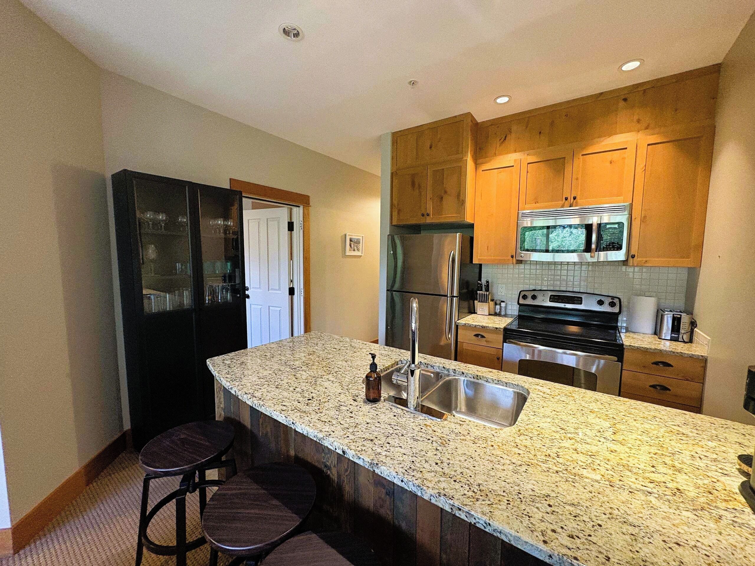 A kitchen with granite countertops, stainless steel appliances, wooden cabinets, and a double sink.