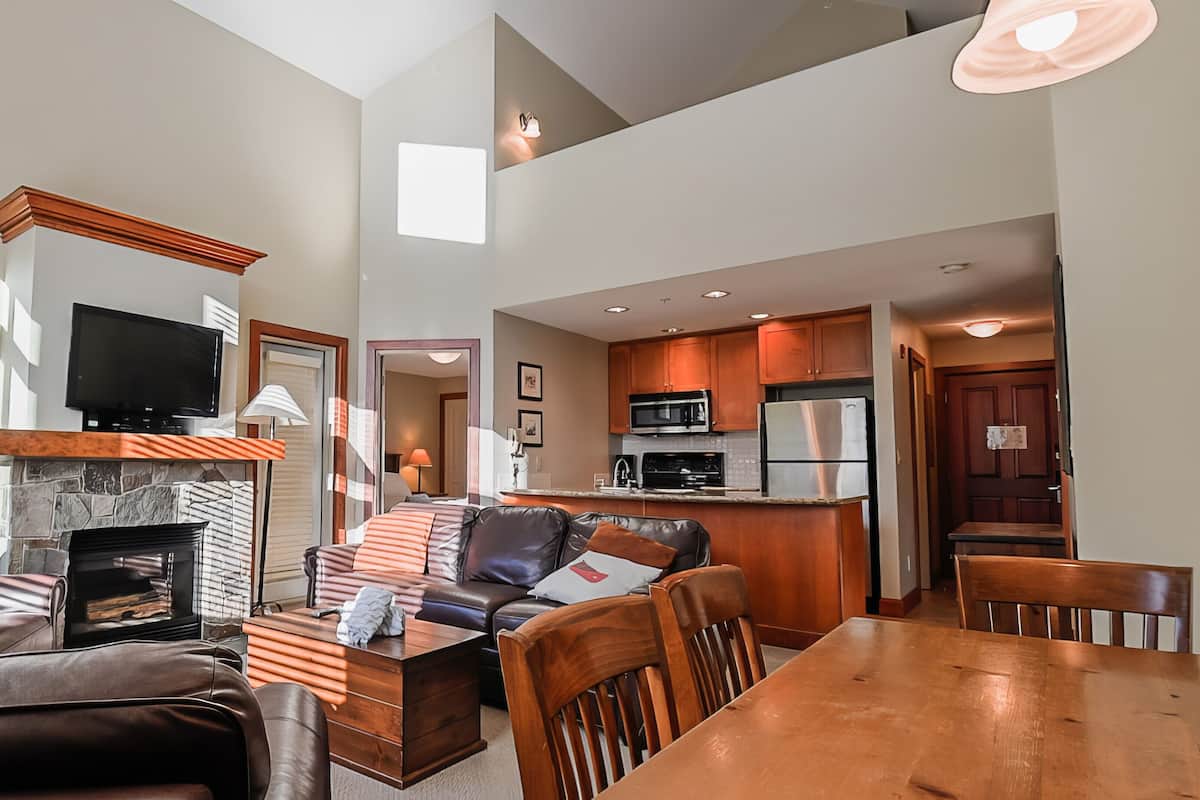 A spacious living room with a fireplace, a television, and a dining area with a wooden table and chairs.