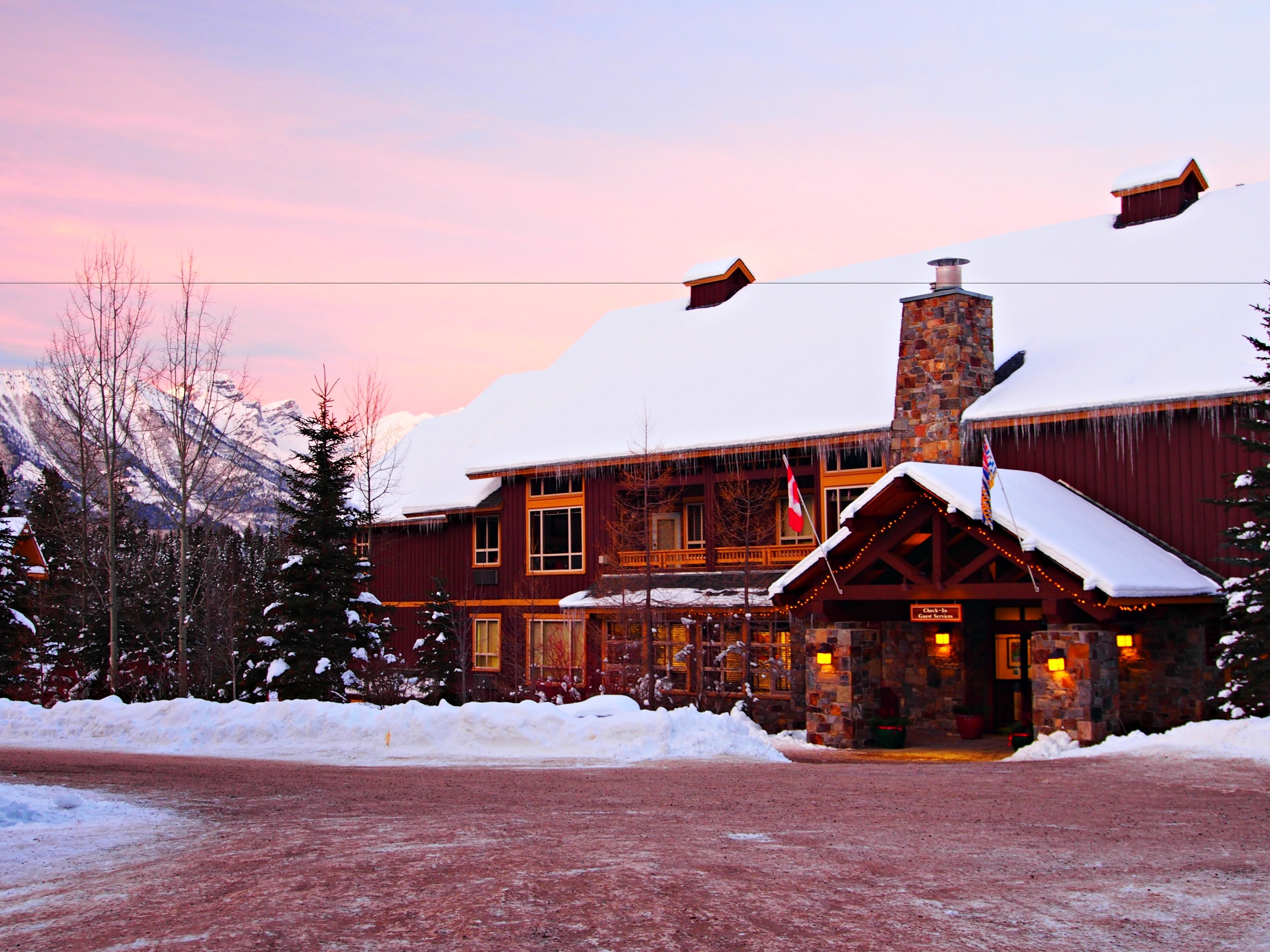 Een lodge met een stenen schoorsteen, houten gevel en een dak bedekt met sneeuw.