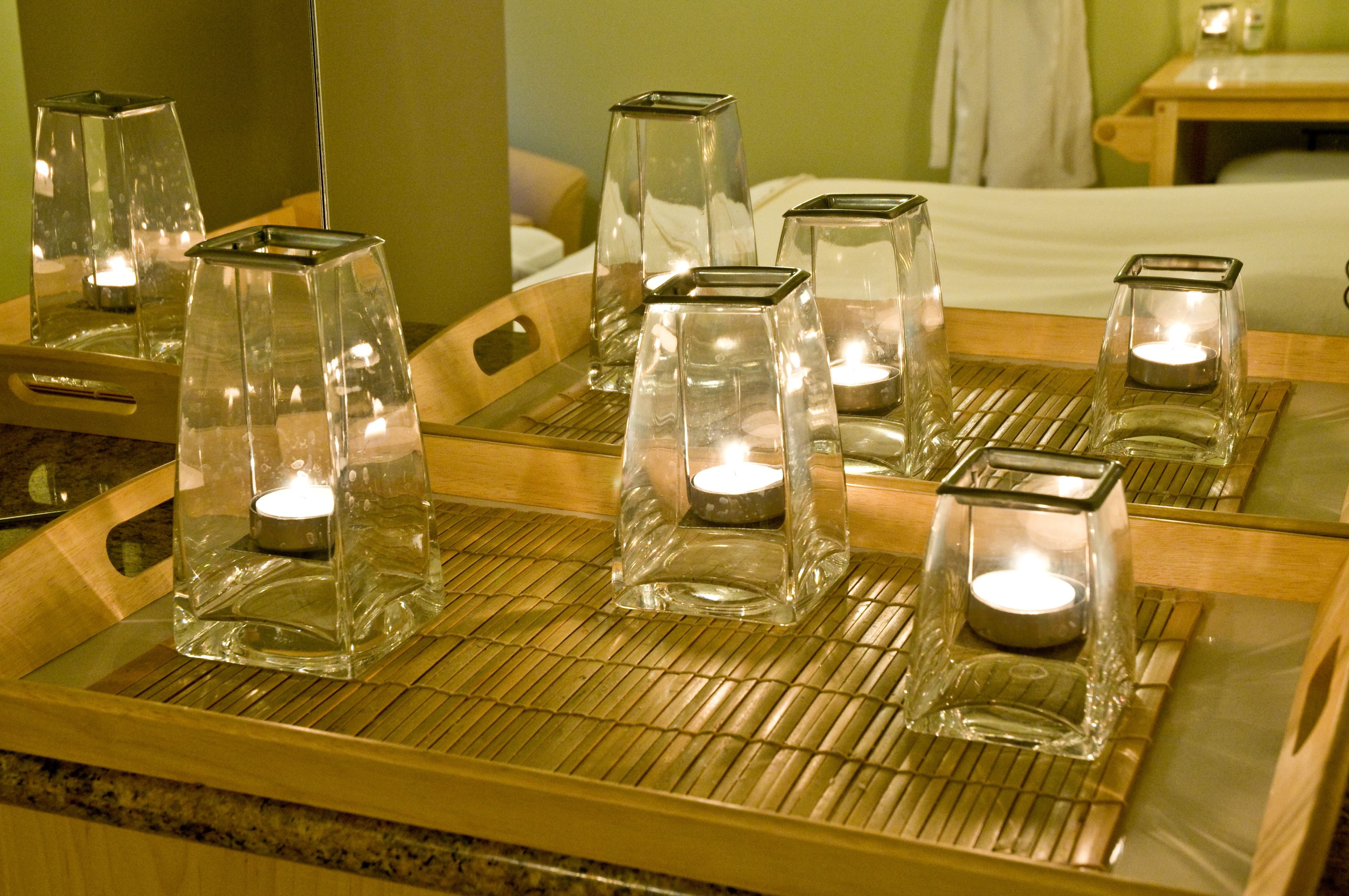 A room with a mirrored tray table displaying several glass candle holders with lit candles.