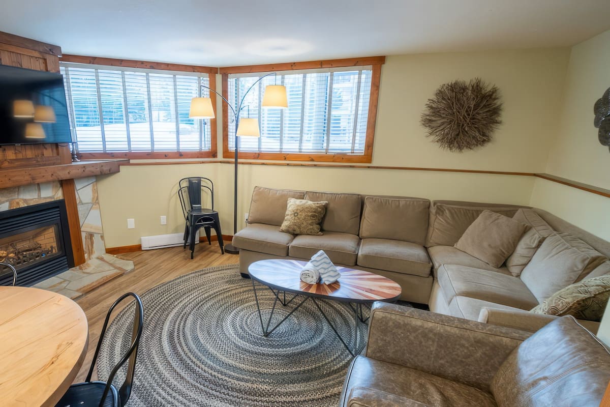 A cozy living room with a fireplace, a sofa, a dining table, and a TV.