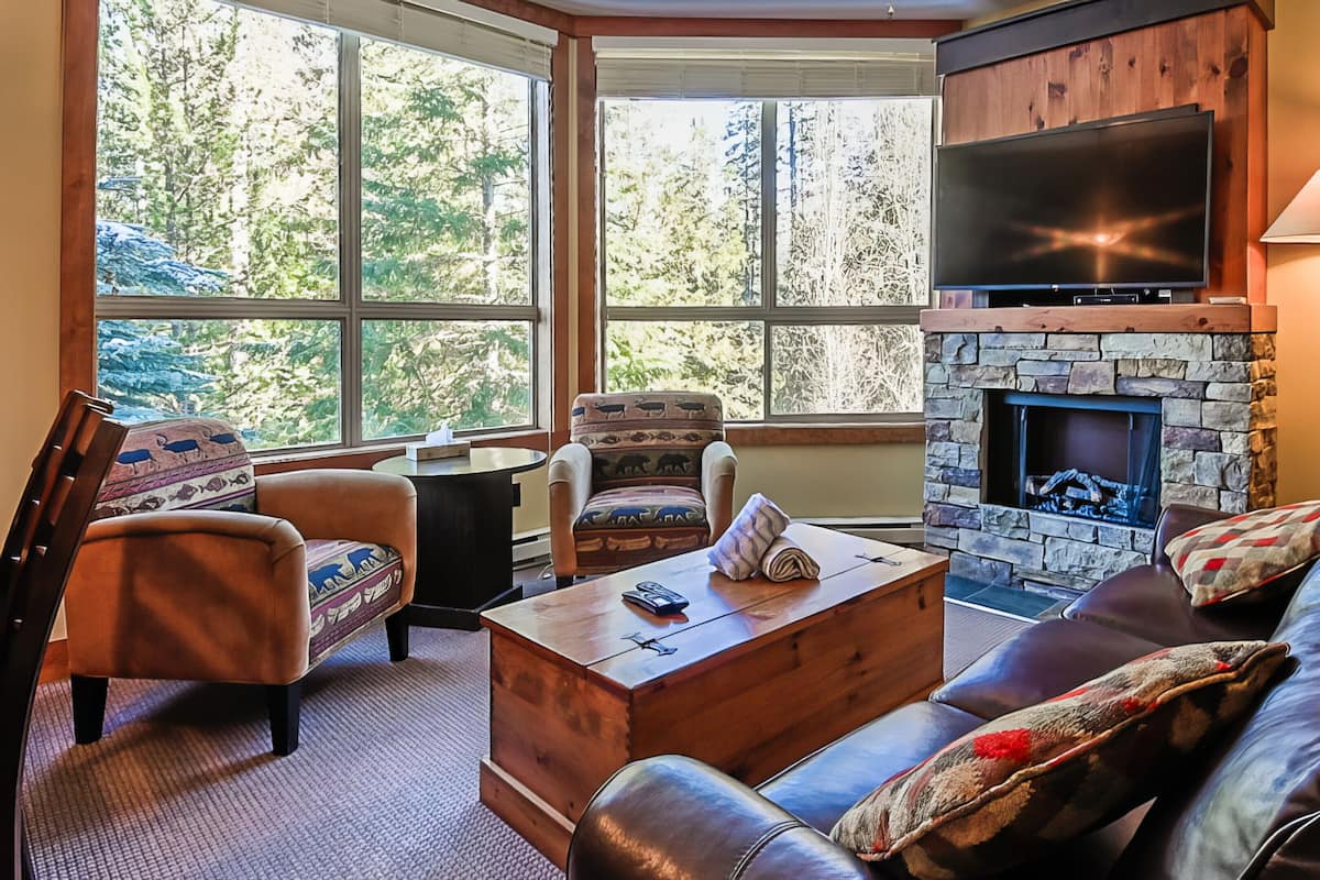 A cozy living room with a stone fireplace, leather sofa, and armchairs.