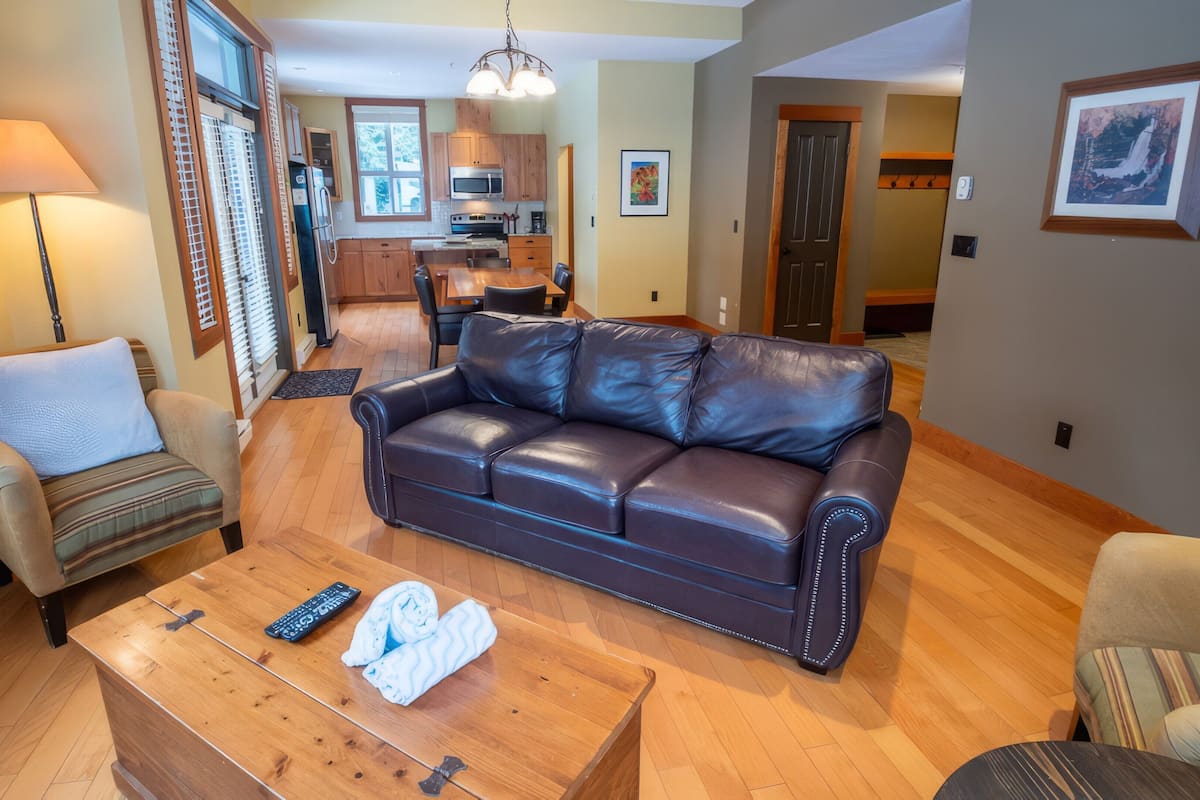 A living room with a leather sofa, a wooden coffee table, and a lamp.