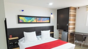 Una habitación de hotel con cama, escritorio, silla y televisor.