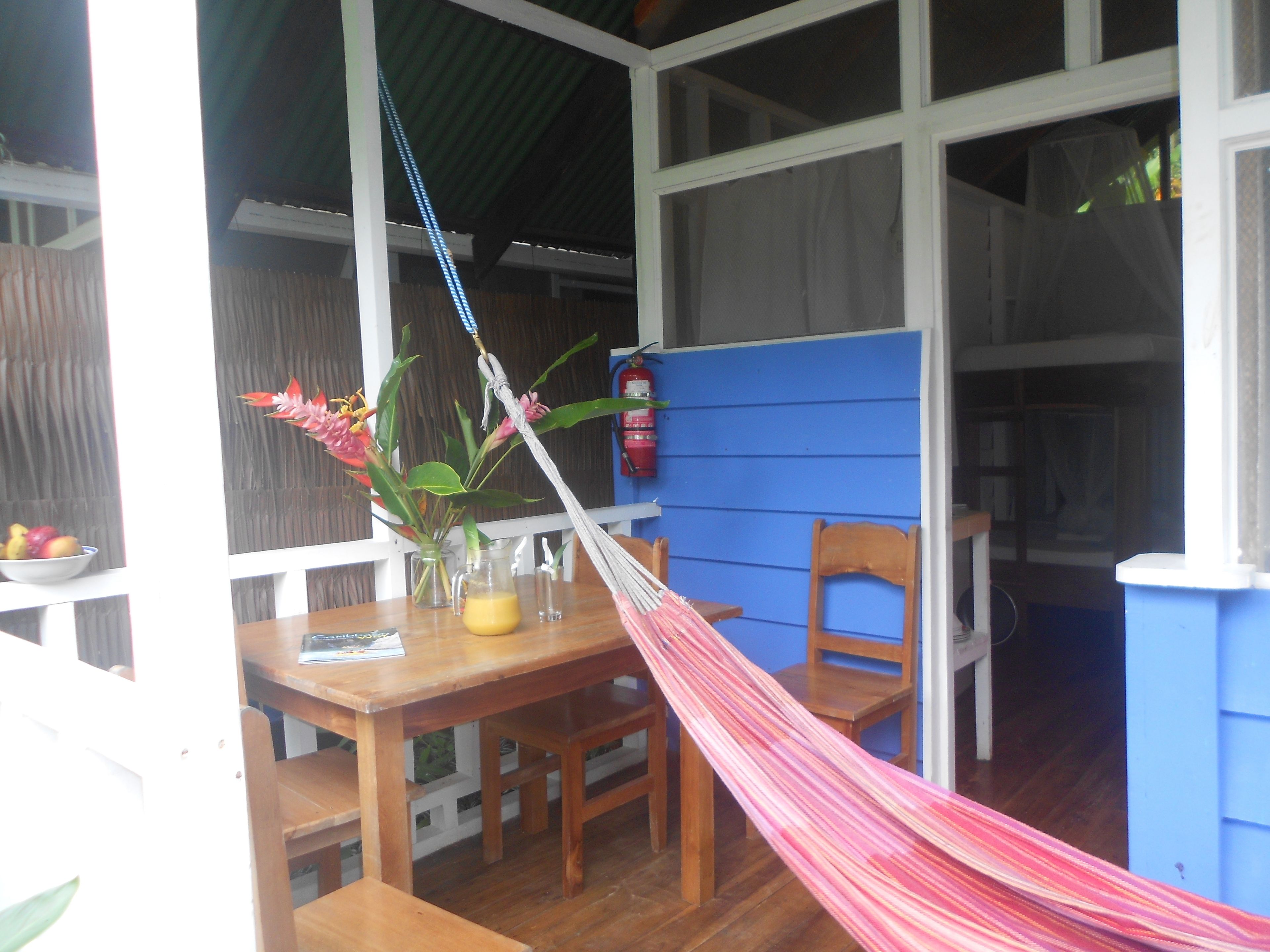 A wooden table with a hammock, a chair, and a vase with flowers.