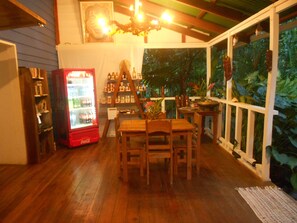 A cozy indoor space with wooden furniture, a Coca-Cola refrigerator, and a variety of bottles on shelves.
