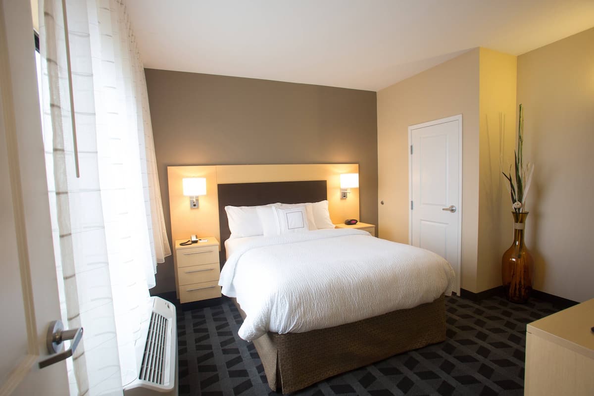 Une chambre d’hôtel avec un grand lit, des lampes de chevet, une table de chevet, un radiateur et une porte.