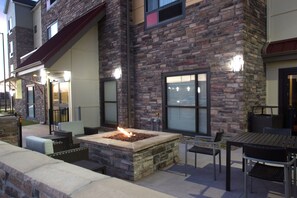 Une terrasse extérieure agrémentée d’un foyer en pierre, de meubles en osier et d’une façade en briques.