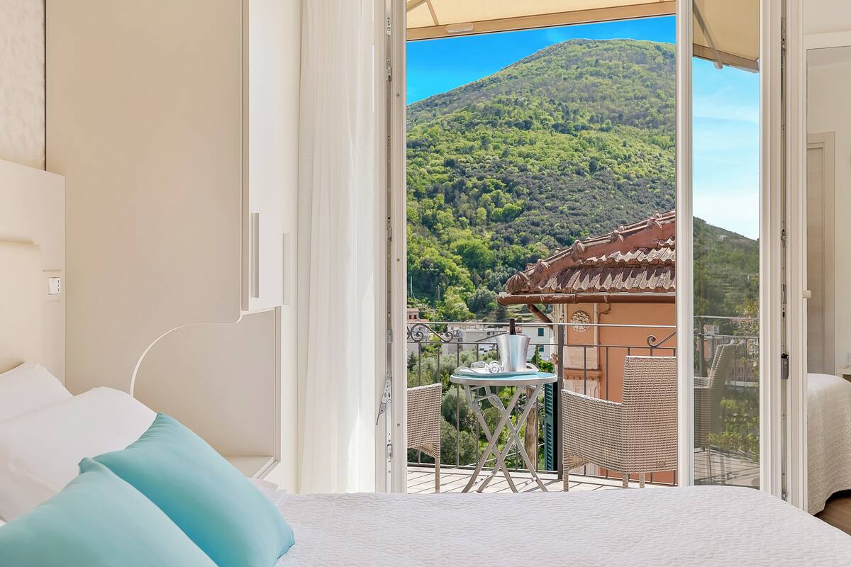 Ein Schlafzimmer mit einem Bett, einem Fenster und einem Balkon mit Blick auf einen Berg und ein Gebäude.