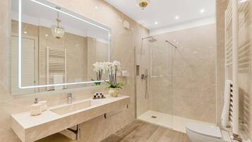 A modern bathroom with a large mirror, a shower, a toilet, and a vanity with a sink.