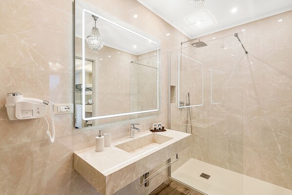 Een moderne badkamer met een grote spiegel, twee wastafels, een douche en een haardroger aan de muur.