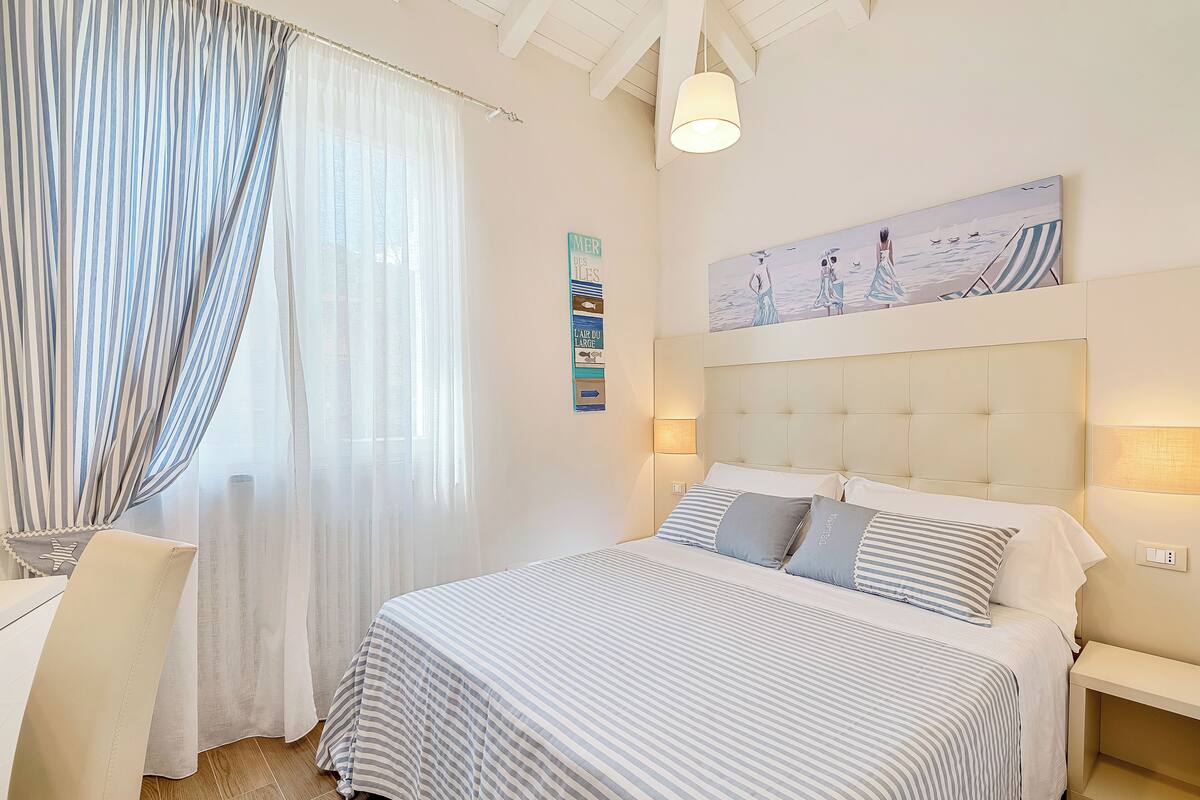 Ein Hotelzimmer mit einem großen Bett, einem Nachttisch, einem Sessel und einem Bild an der Wand.
