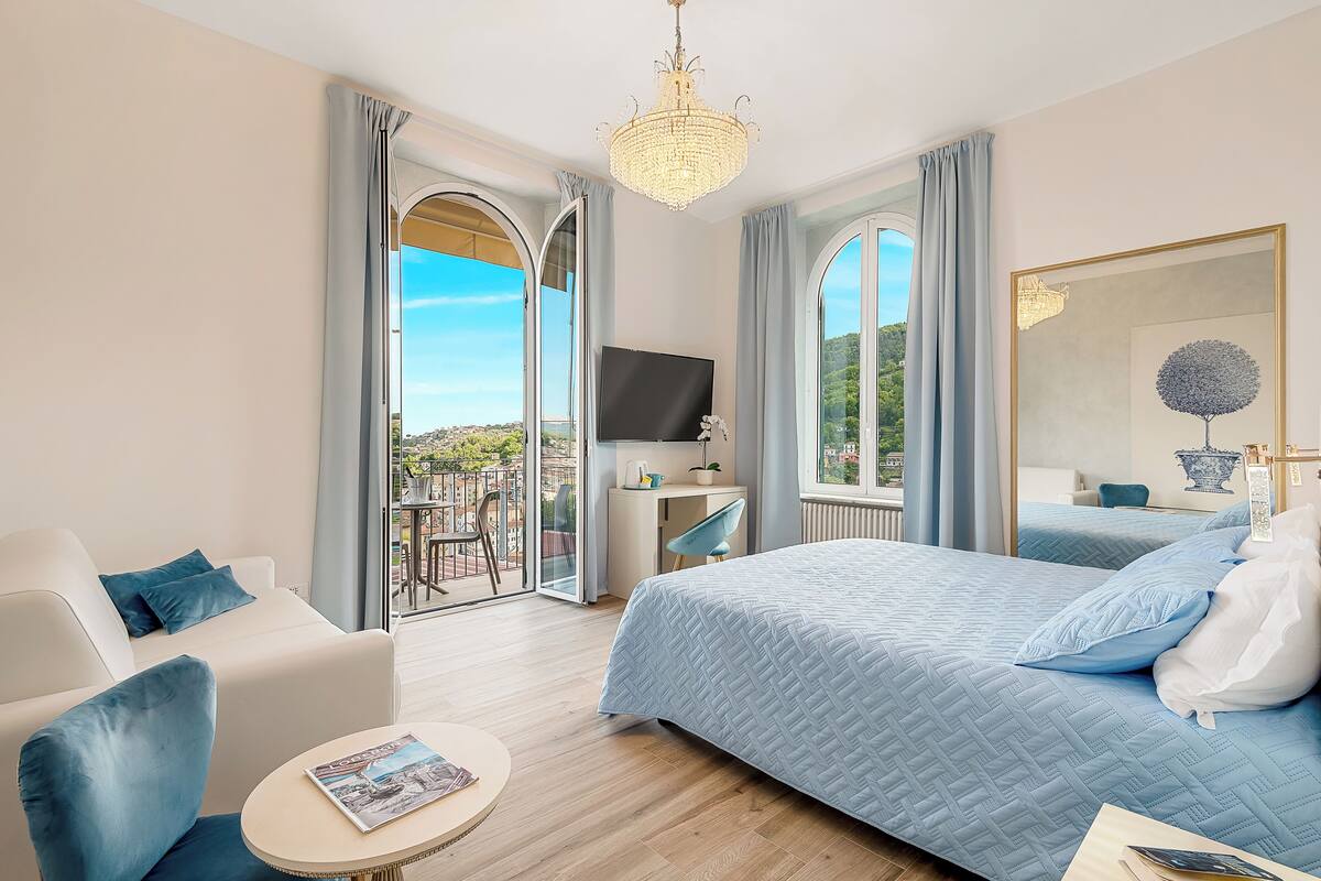 Ein Hotelzimmer mit einem großen Bett, einem Schreibtisch, einem Fernseher und einem Balkon mit Blick.