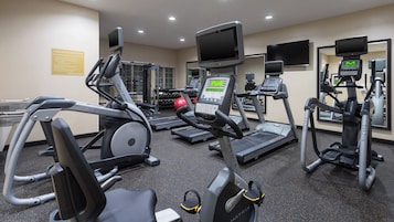 Un gimnasio con cintas de correr, elípticas y máquinas de pesas.