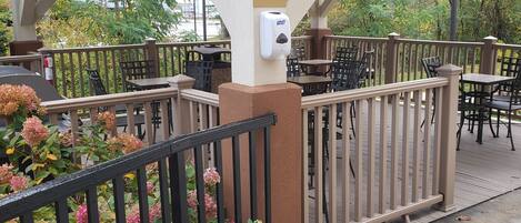 An outdoor patio area with tables and chairs, a sign indicating BBQ supplies are available at the front desk, and a security gate.