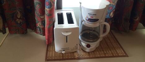 A kitchen area with a toaster and a coffee maker on a mat.