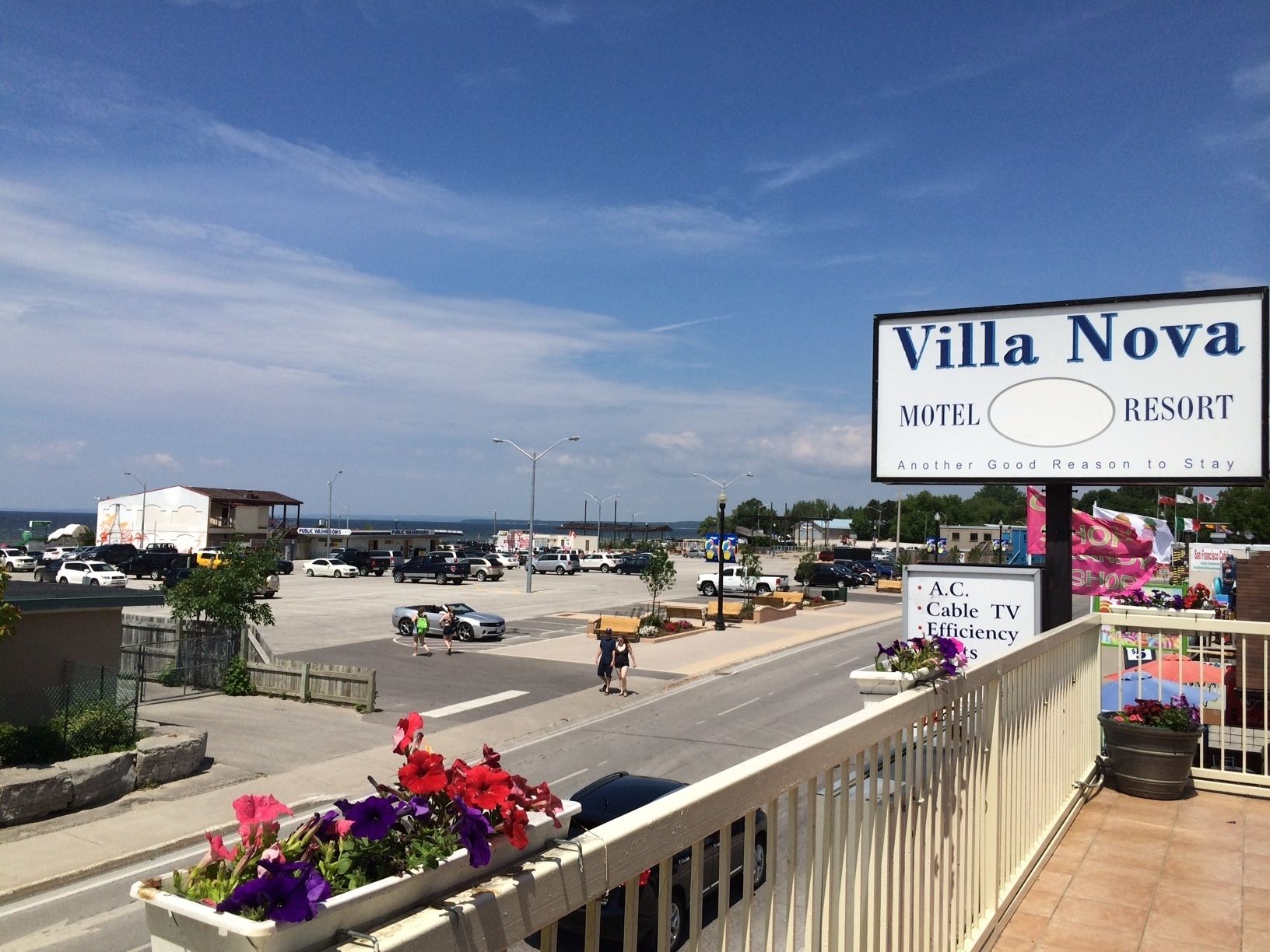 A sign for Villa Nova Motel & Resort with a view of the parking lot and street.
