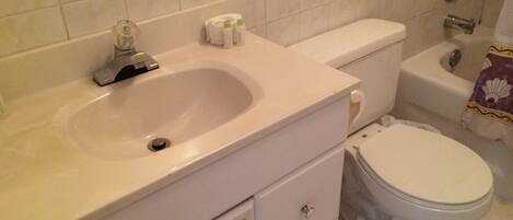 A bathroom with a sink, toilet, and a shower area.