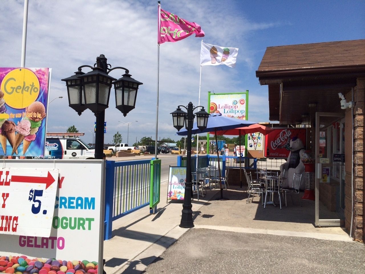 A storefront with a sign advertising Gelato and Lollipop, outdoor seating, and a Coca-Cola sign.