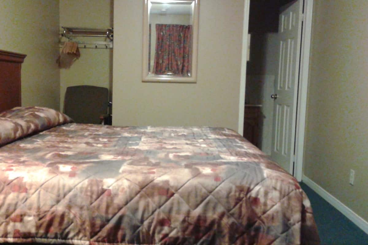 Une chambre à coucher avec un lit, une chaise, un porte-manteau et une porte.