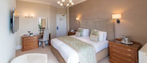 A bedroom with a bed, bedside tables, a dresser, a chair, a desk, and a mirror.