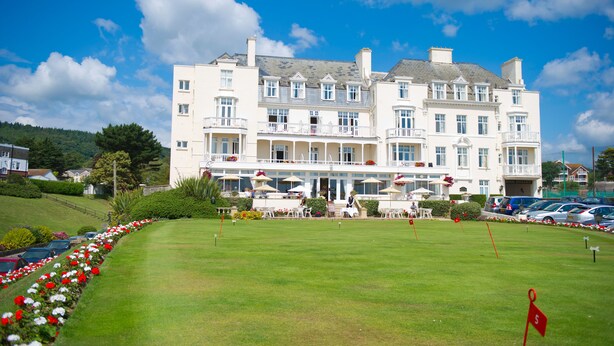 A large, multi-story hotel with a well-maintained lawn and outdoor seating area. - The Belmont Hotel - Adults Only (Sidmouth)
