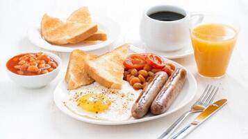 A breakfast plate with toast, beans, tomatoes, sausages, and a fried egg.