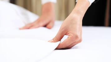 A close-up of a hand adjusting a white sheet on a bed.