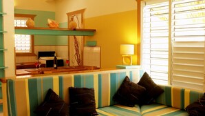 Un soggiorno con tavolino in legno, un divano a righe e un'area cucina sullo sfondo.