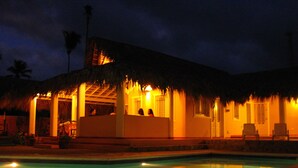 Un edificio con piscina, tetto di paglia e facciata ben illuminata.