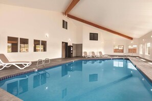 A large indoor swimming pool with clear blue water, surrounded by lounge chairs and a wooden ceiling. - Country Inn & Suites by Radisson, Prineville, OR (Prineville)