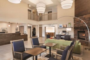 A spacious lobby with a high ceiling, a fireplace, and a reception desk. - Country Inn & Suites by Radisson, Prineville, OR (Prineville)