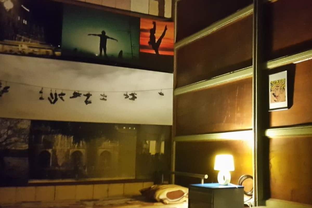 Ein Hotelzimmer mit einem Bett, einem Nachttisch, einer Lampe und einer Wand mit gerahmten Bildern.