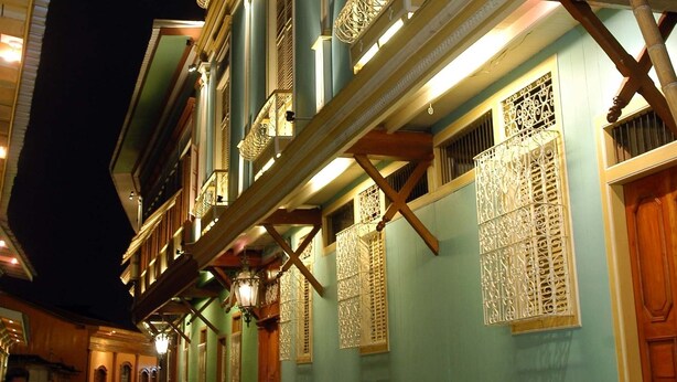 Un edificio tradicional con un balcón y celosías decorativas en las ventanas.
