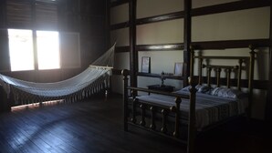 Una habitación con cama con dosel, una hamaca y suelo de madera.