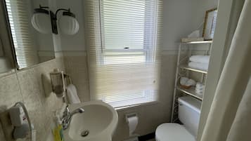 A bathroom with a sink, toilet, and window with blinds.