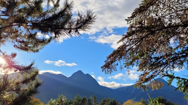 A parking lot with a building in the background, surrounded by trees and mountains. - Ridgeview Motor Inn (Gold River)