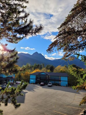 A parking lot with a building in the background, surrounded by trees and mountains. - Ridgeview Motor Inn (Gold River)