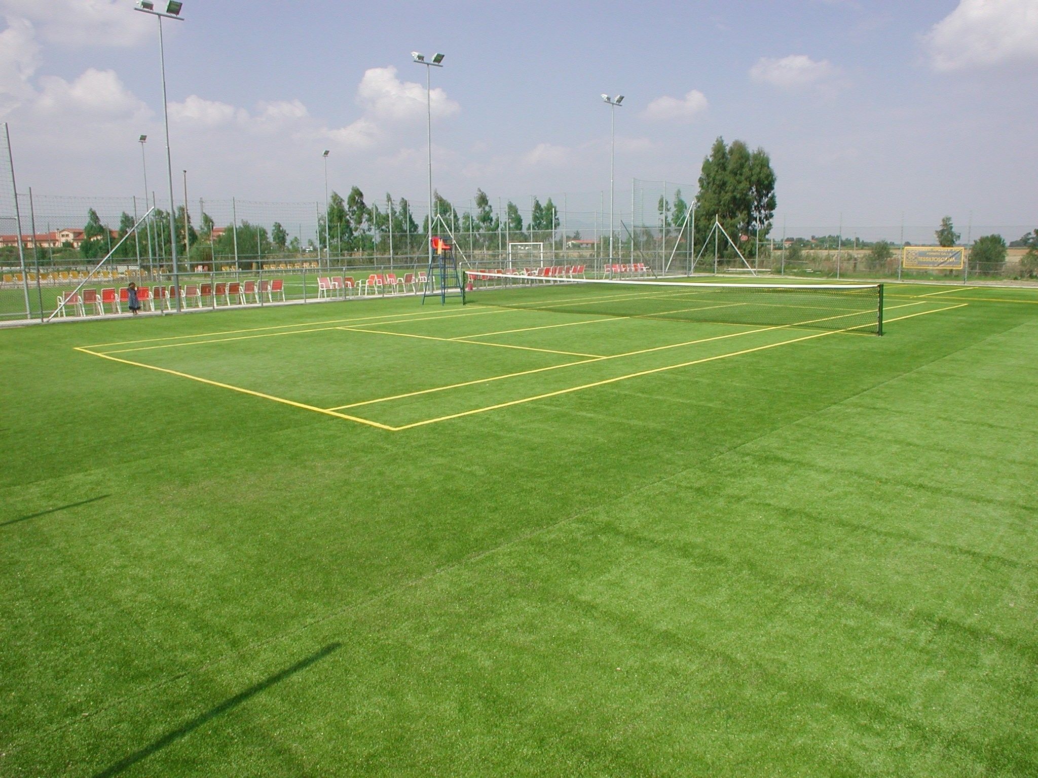 Un campo sportivo con un palo della porta, fari e gradinate per il pubblico.