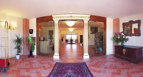 A grand entrance with a tiled floor, a central archway, and a chandelier.