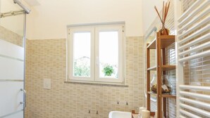 A bathroom with a bidet, toilet, and sink. There is a window above the sink and a towel rack with towels. - B&B La Terrazza (Rho)