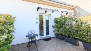 A patio with a table and chairs, a door with the number 2, and potted plants. - B&B La Terrazza (Rho)