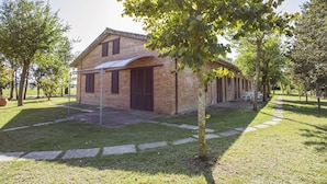 A brick building with a covered patio area, surrounded by trees and a well-maintained lawn.