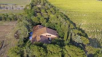 Vista aérea de una propiedad rural con una extensa viña, una casa con techo rojo y abundante vegetación.