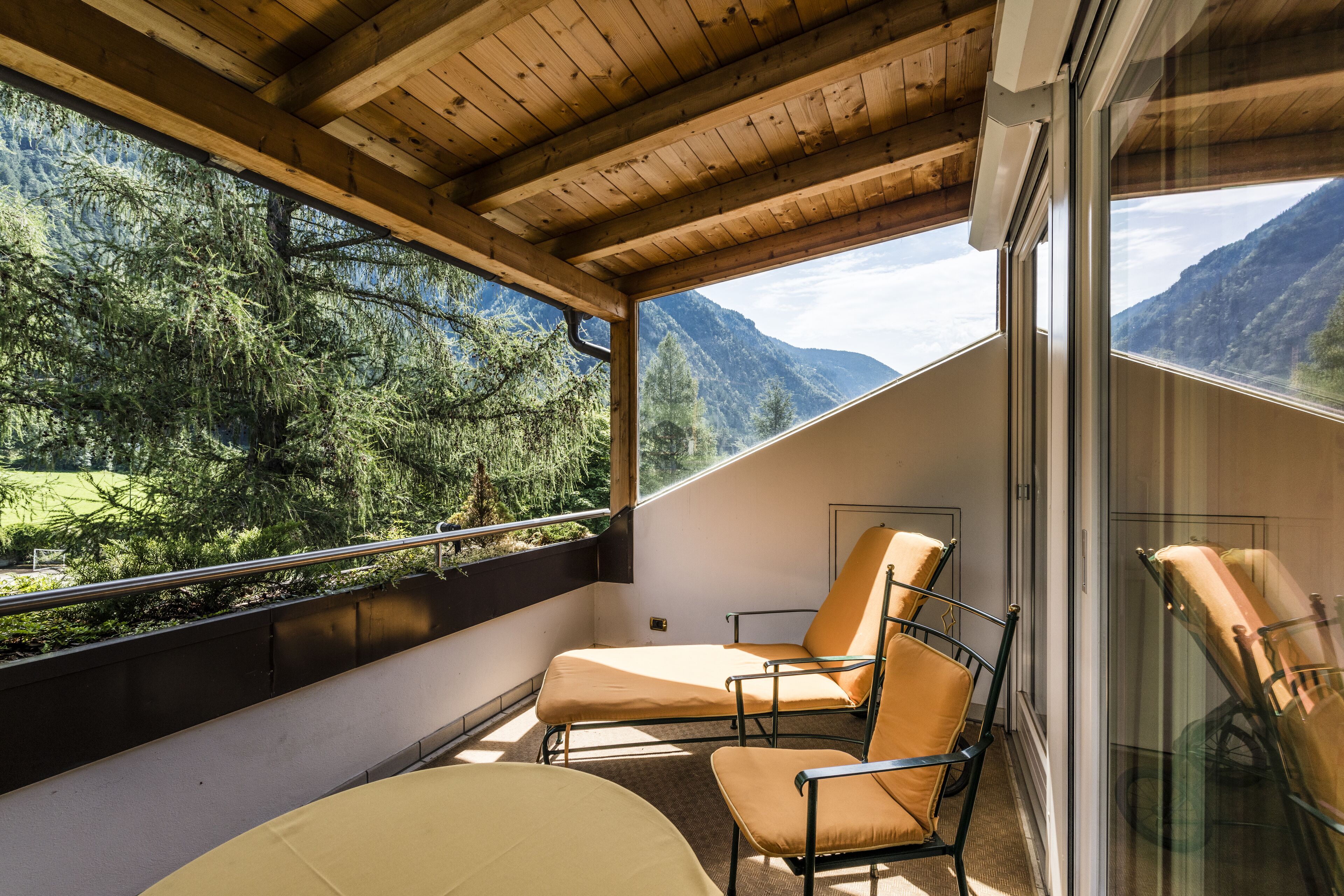 Un balcón con dos sillones de descanso, una puerta de vidrio y vistas a un paisaje montañoso.