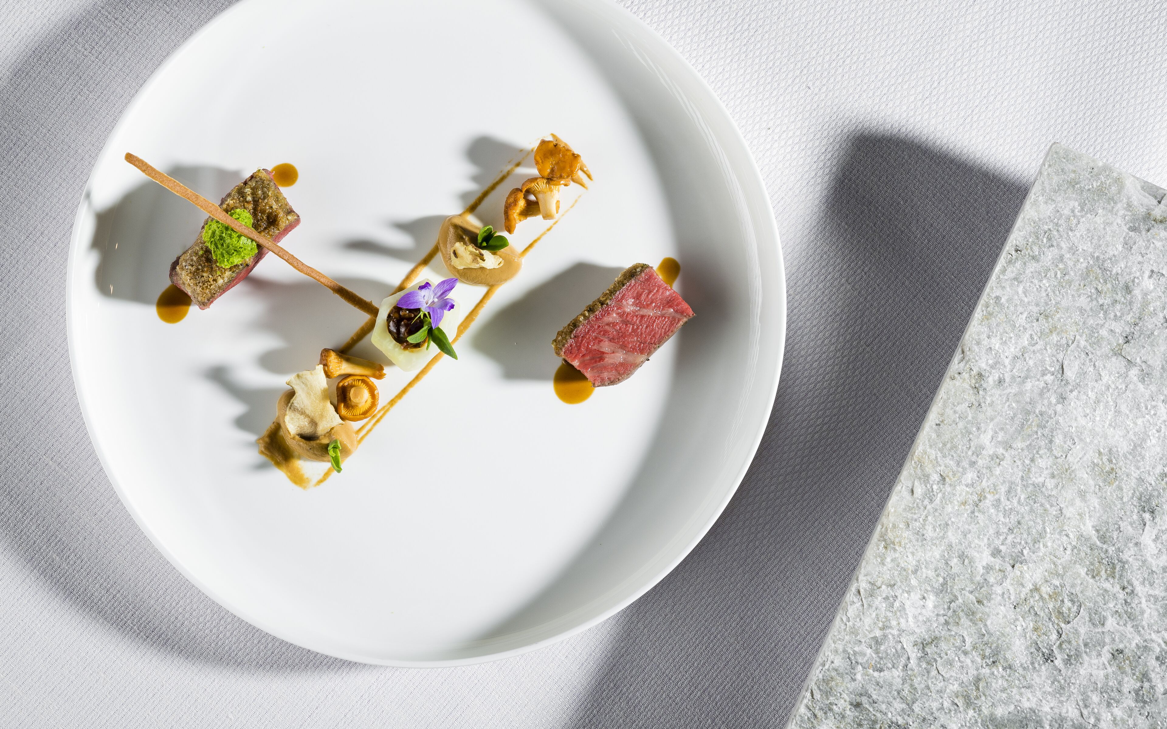 Une assiette blanche sur laquelle sont disposés quatre aliments, le tout présenté sur une surface texturée.