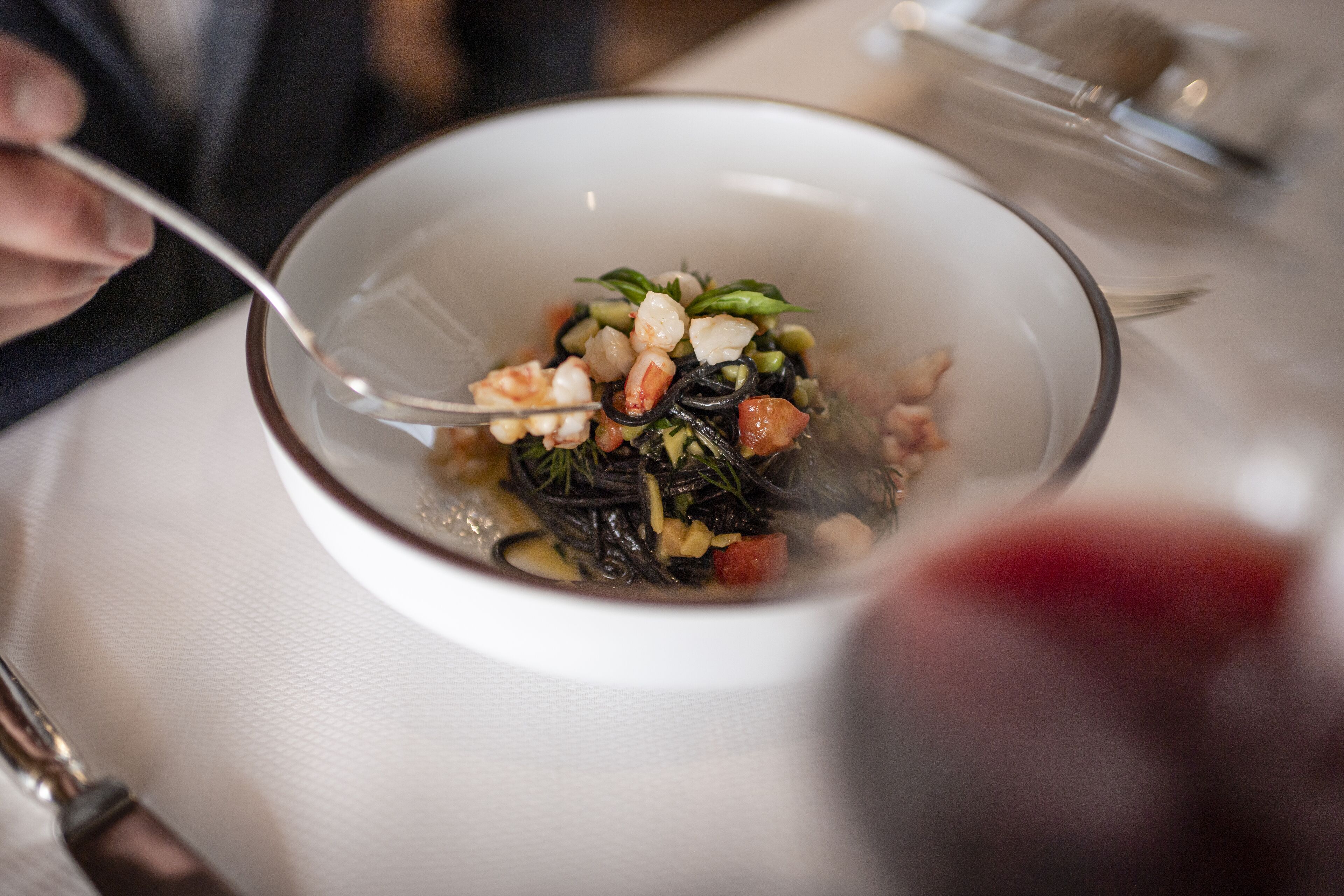A bowl of pasta with vegetables and shrimp.
