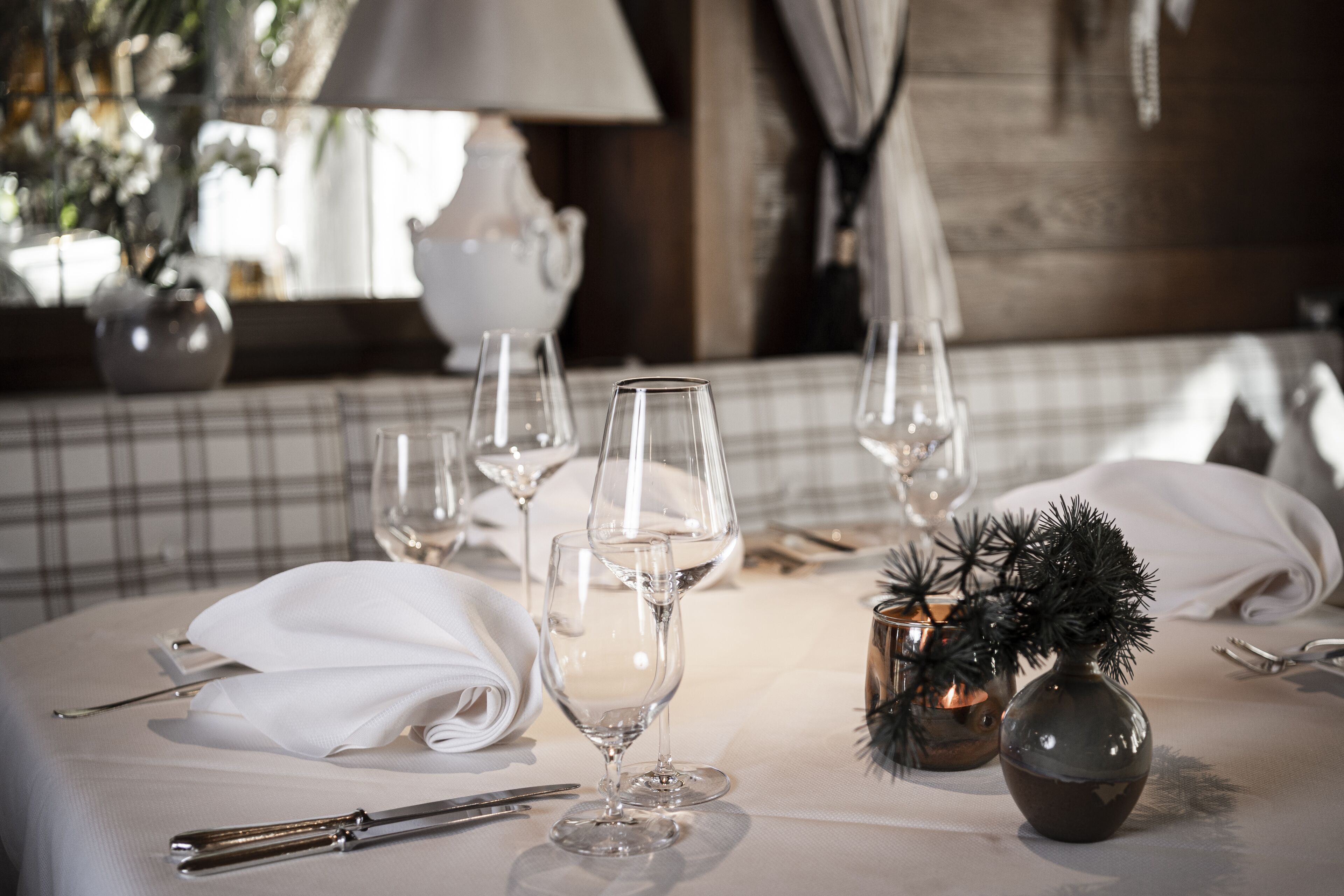 Una mesa lista para una comida, con copas de vino, cubiertos y un candelabro.